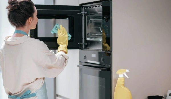 Cleaning the kitchen. Housewife in yellow gloves cleaning the kitchen