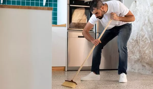young man sweeping a floor perfectly