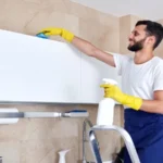 Man cleaning kitchen surface high up standing on a ladder. Cleaning service concept