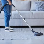 Woman vaccum and cleaning living room floor or carpet for home hygiene housework