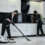 Cleaning service company employees removing cleaning kitchen with professional steam cleaner equipment