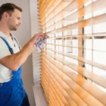 Handyman cleaning blinds with a towel