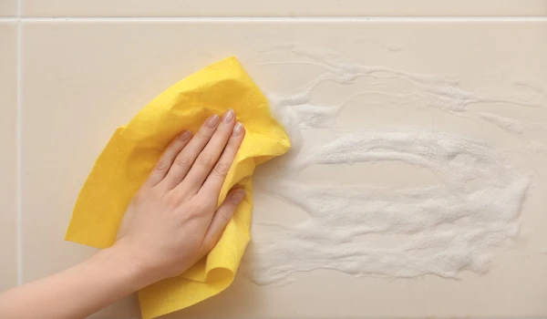 Woman cleaning wall in bathroom