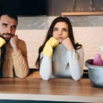 Wondering couple doing house cleaning in modern kitchen at home