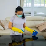 Young woman cleaning the table with disinfectant