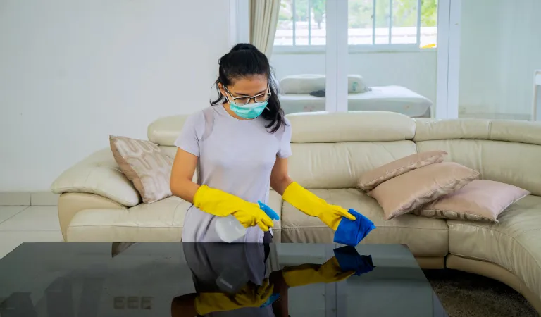 Young woman cleaning the table with disinfectant