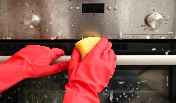 Cleaning oven steel with sponge. concept of cleaning at home